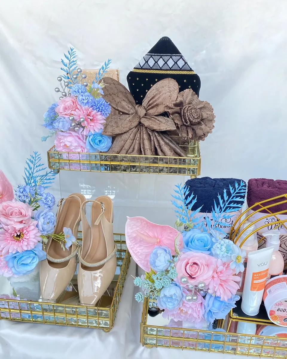Nampan cermin emas berisi sepatu, mukena, dan perawatan tubuh, dengan bunga pink dan biru muda